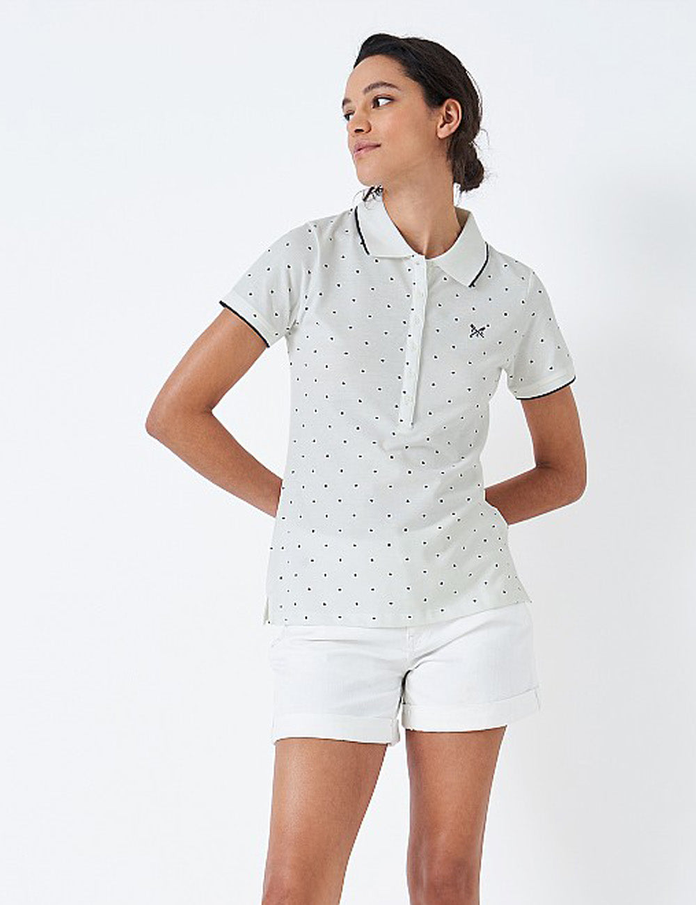 Woman wearing the Classic Polo Shirt with white shorts and her hands behind her