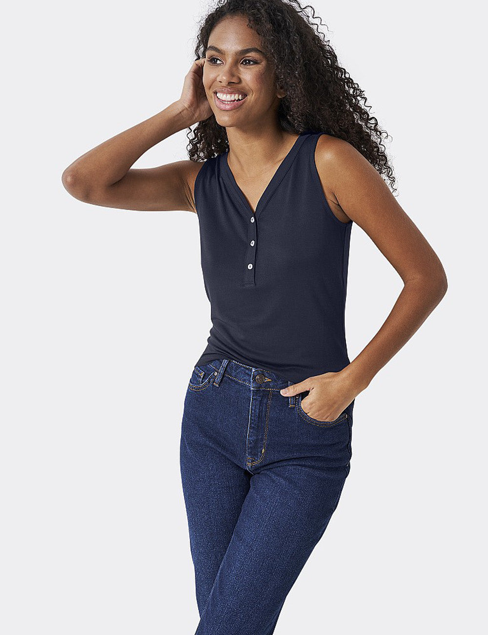Woman wearing the Henley Vest with jeans, her left hand in the front pocket and her right hand in her hair