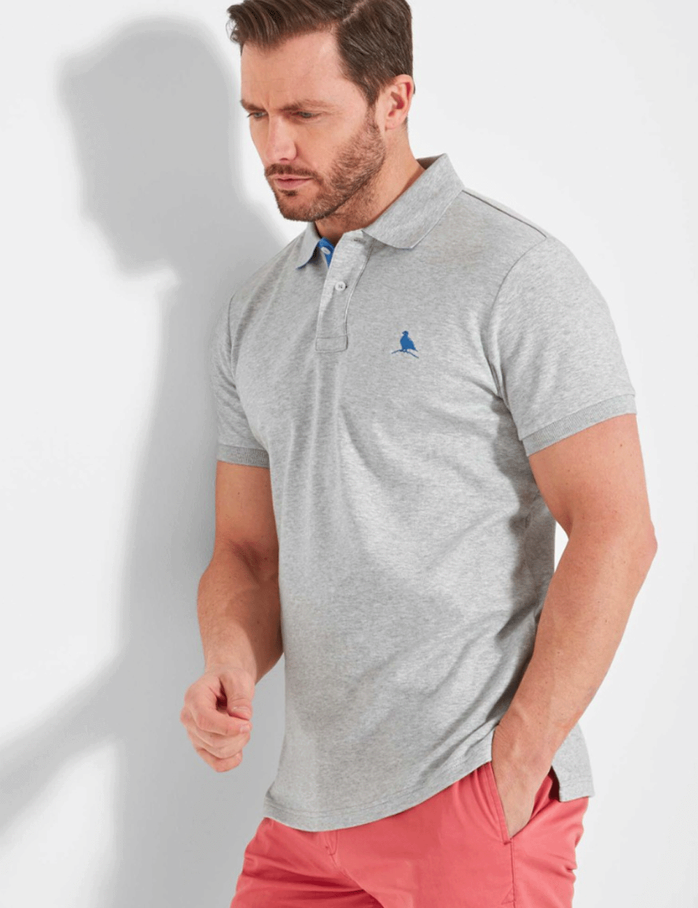 Man leaning against a white wall wearing the St. Ives Polo