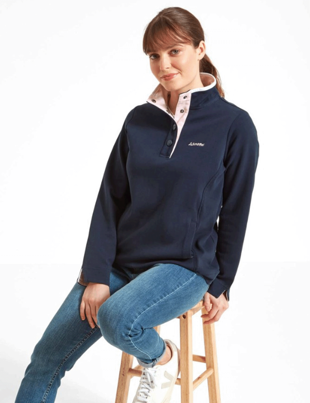 Woman sitting on a stool wearing the Steephill Cove Sweatshirt in Navy