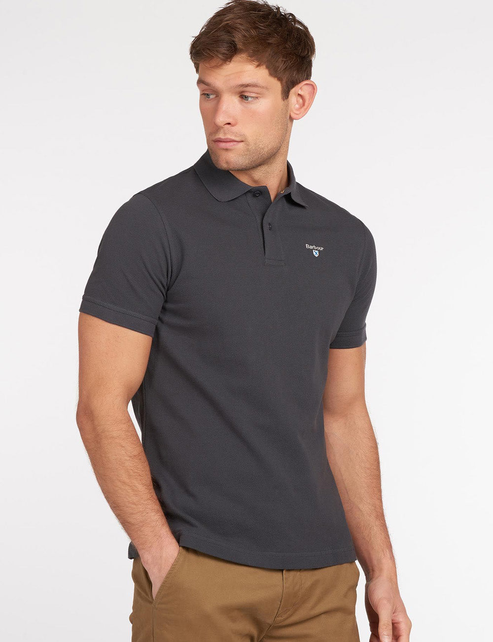 Man wearing the Barbour Sports Polo in Navy with beige shorts - with his hand in the front right pocket of the shorts